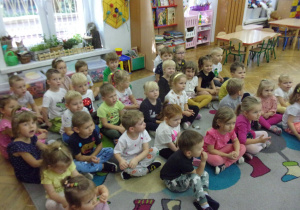 Smyki i Tuptusie na dywanie oglądają prezentację na tablicy interaktywnej