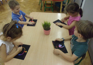 Smyki wykonują pracę plastyczną przy stolikach