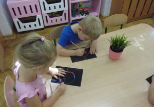 Smyki wykonują pracę plastyczną przy stolikach