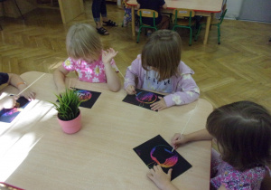 Smyki wykonują pracę plastyczną przy stolikach