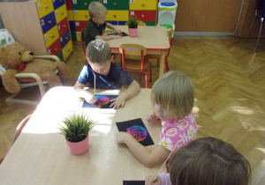 Smyki wykonują pracę plastyczną przy stolikach