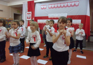 Juniorzy śpiewają piosenkę na tle dekoracji z okazji Dnia Niepodległości