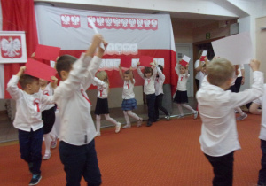 Juniorzy idą po kole trzymając kartki czerwone, białoczerwone i białe