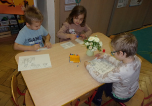 Żaczki przy stoliczkach podczas składania obrazka z części