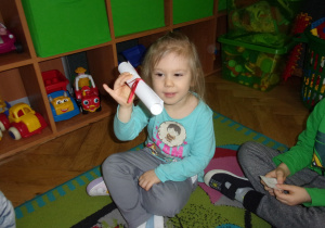 dziewczynka trzyma zwinięty list