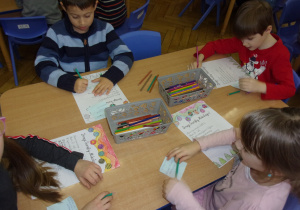 Juniorzy przy stoliczkach przygotowują listy do Mikołaja