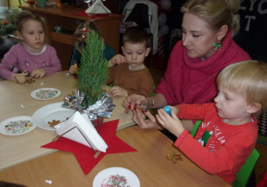 Żaczki przy stoliczkach ozdabiają świąteczne pierniczki