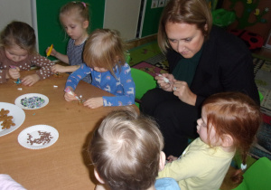 Tuptusie przy stoliczkach ozdabiają świąteczne pierniczki